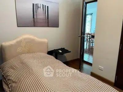 Cozy bedroom with single bed and serene wall art, leading to a bright dining area.