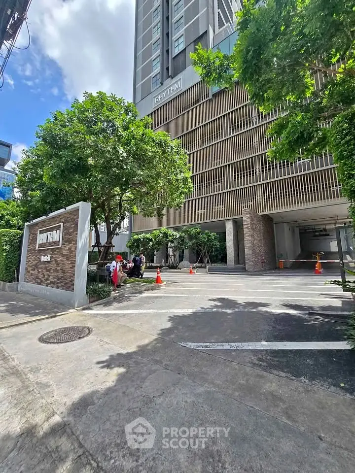 Modern condominium entrance with lush greenery and sleek architectural design.