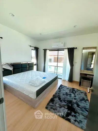 Spacious bedroom with modern decor and large windows offering natural light.