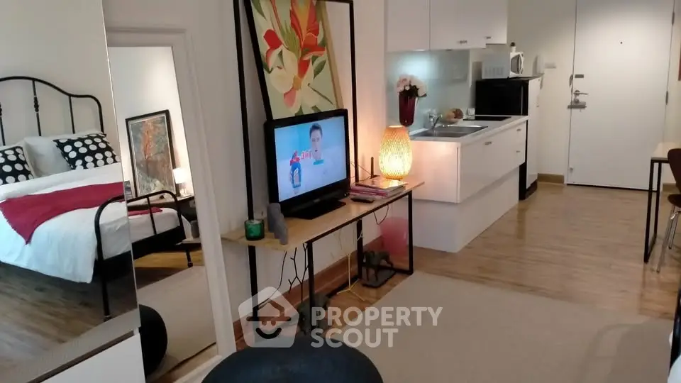 Modern studio apartment with open kitchen and cozy bedroom area, featuring stylish decor and wooden flooring.