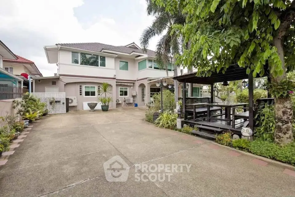 Spacious two-story house with lush garden and outdoor seating area, perfect for family living.