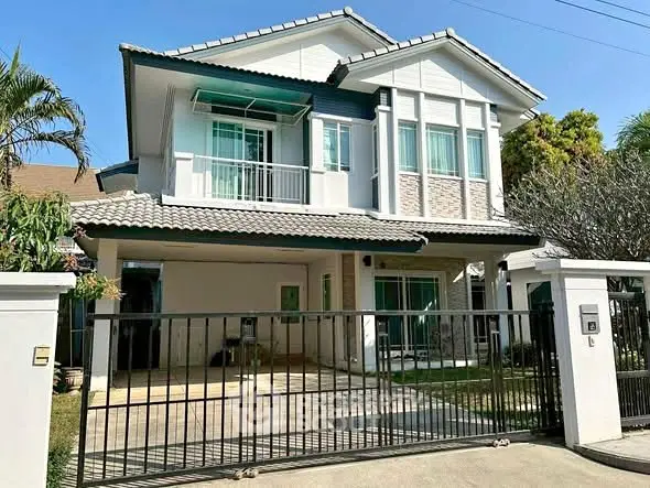 Charming two-story house with gated entrance and lush greenery, perfect for family living.