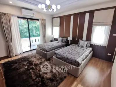 Spacious bedroom with twin beds, elegant decor, and balcony access in a luxurious home.