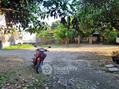 Spacious outdoor area with lush greenery and a parked motorcycle, ideal for garden enthusiasts.