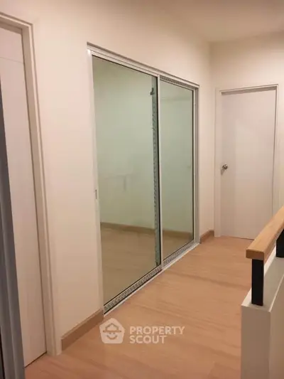 Modern hallway with sliding glass doors and wooden flooring in a contemporary home.