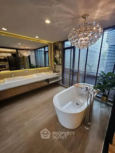 Luxurious bathroom with freestanding tub, dual sinks, and elegant lighting in modern home.
