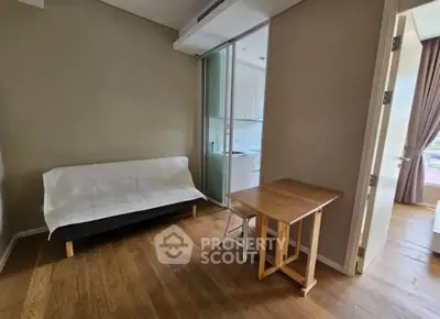 Cozy living room with wooden flooring and compact furniture, adjacent to a modern kitchen.