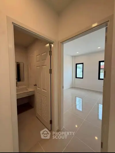 Modern apartment interior with bathroom and bright room, sleek tile flooring, and minimalist design.