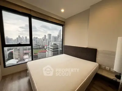 Modern bedroom with stunning city view from large window, featuring a comfortable bed and stylish decor.