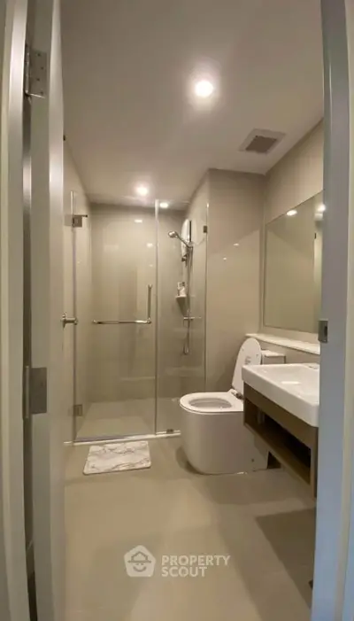 Modern bathroom with glass shower and sleek fixtures in contemporary apartment.