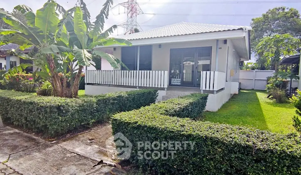 Charming single-story house with lush garden and cozy front porch.
