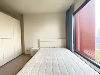 Bright bedroom with large window and modern furniture in urban apartment.