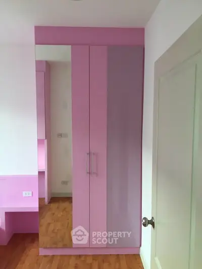 Modern pink wardrobe with mirrored doors in a stylish bedroom setting.