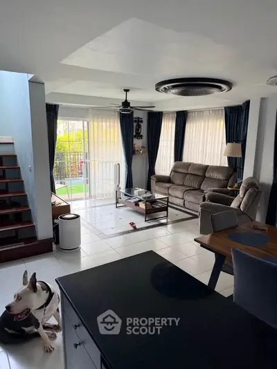 Spacious living room with modern furniture and large windows overlooking a garden.