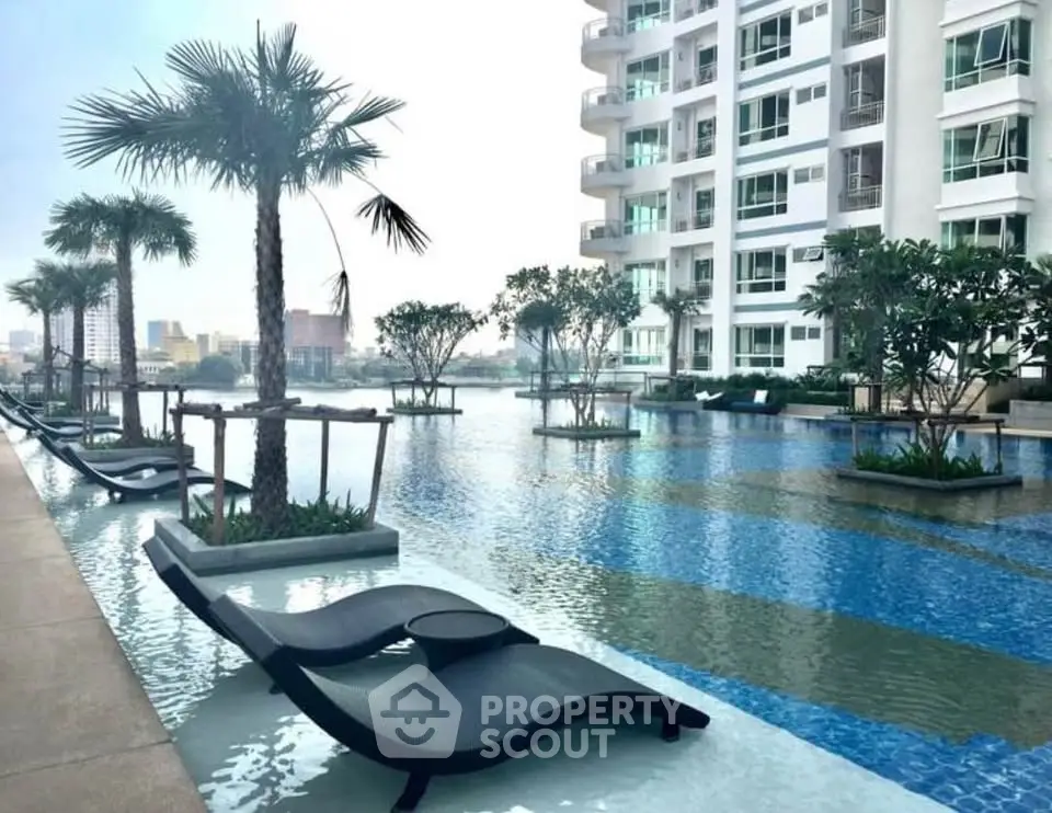 Luxurious condominium pool area with modern lounge chairs and palm trees, offering a serene urban oasis.