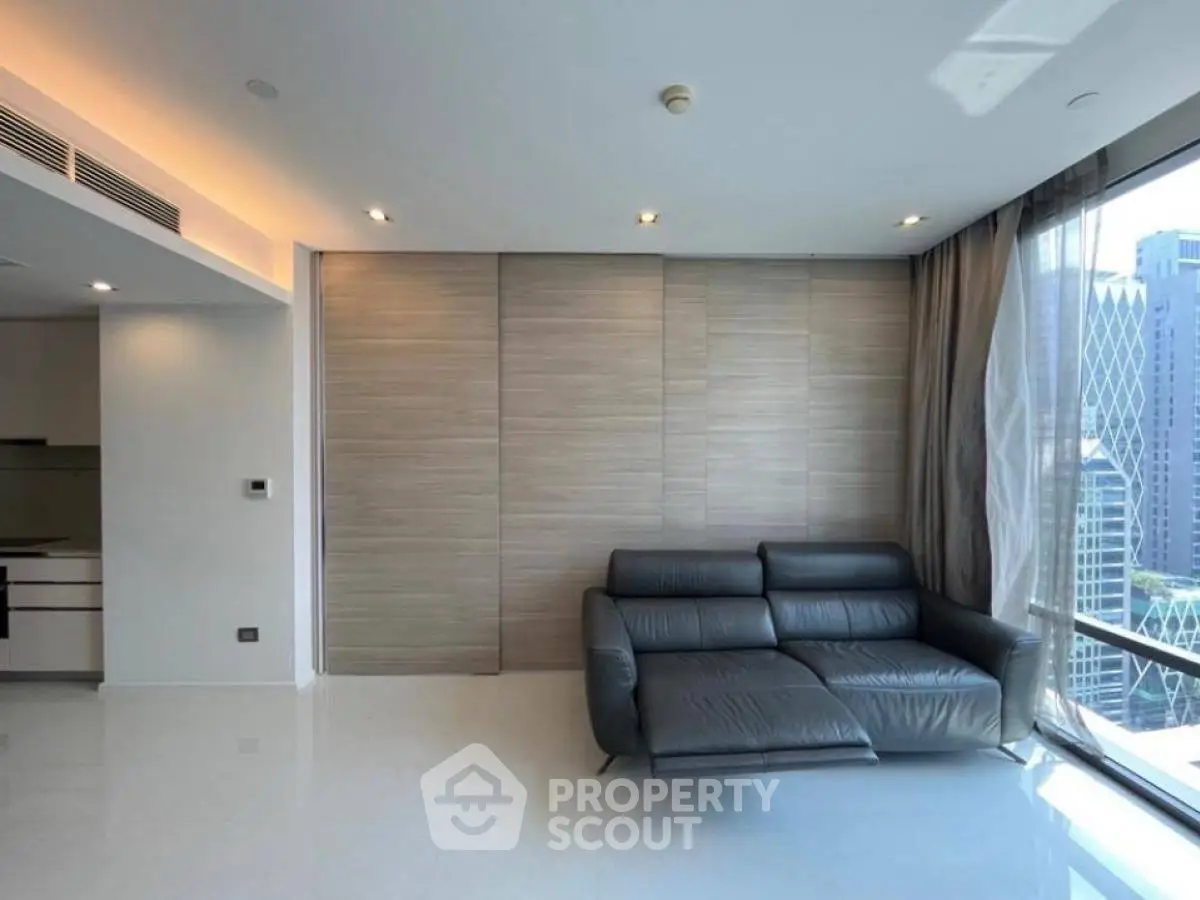 Modern living room with sleek black sofa and city view through large windows.