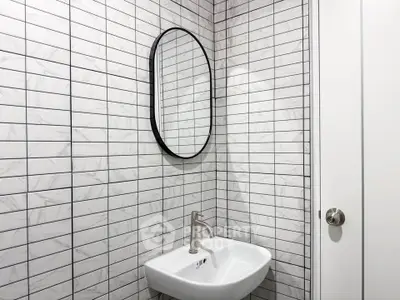 Modern minimalist bathroom with sleek white sink and stylish oval mirror.