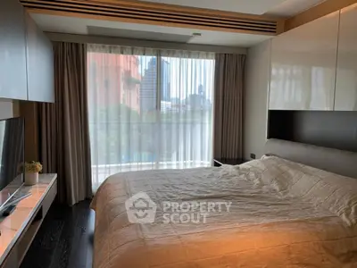 Modern bedroom with large window and city view, featuring sleek furniture and cozy bedding.
