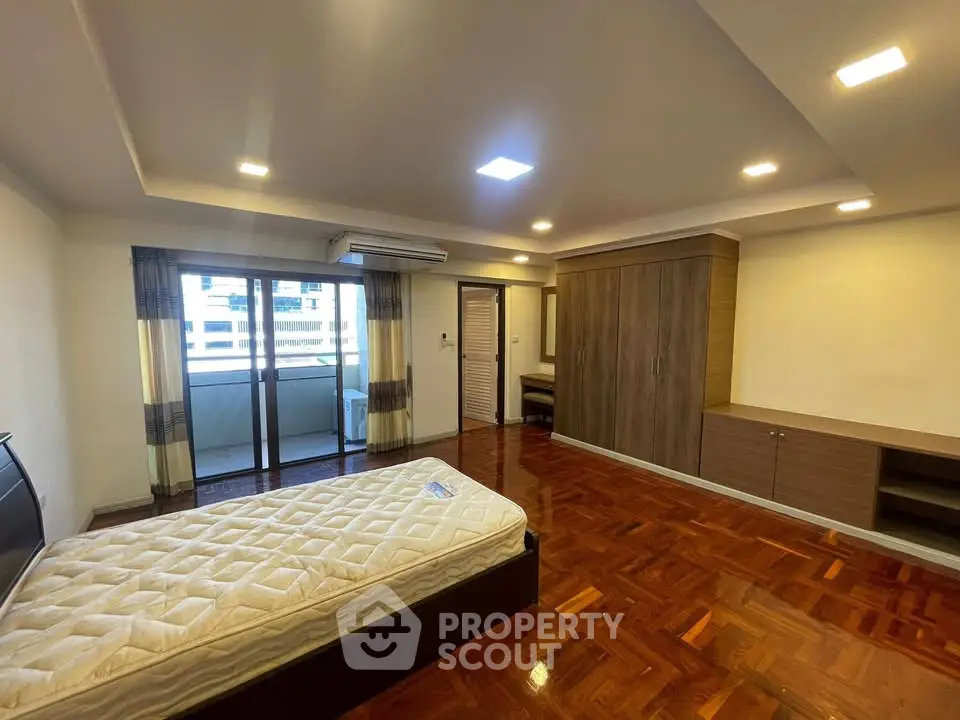 Spacious bedroom with wooden flooring and large windows in modern apartment