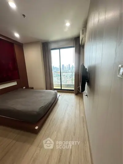 Modern bedroom with city view, featuring sleek design and large window for natural light.
