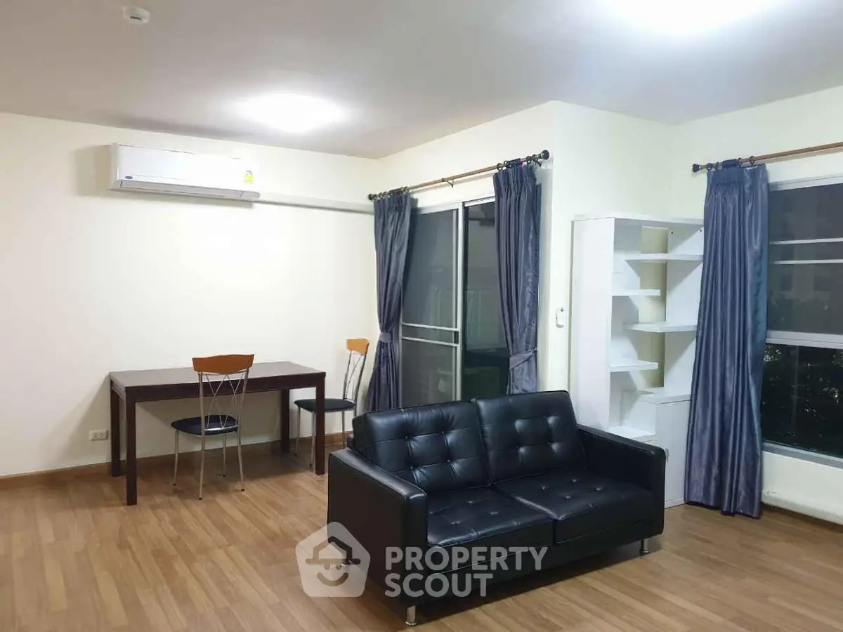 Modern living room with black leather sofa, dining table, and large window with curtains.