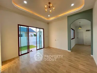 Spacious modern living room with elegant lighting and large sliding doors opening to a garden view.