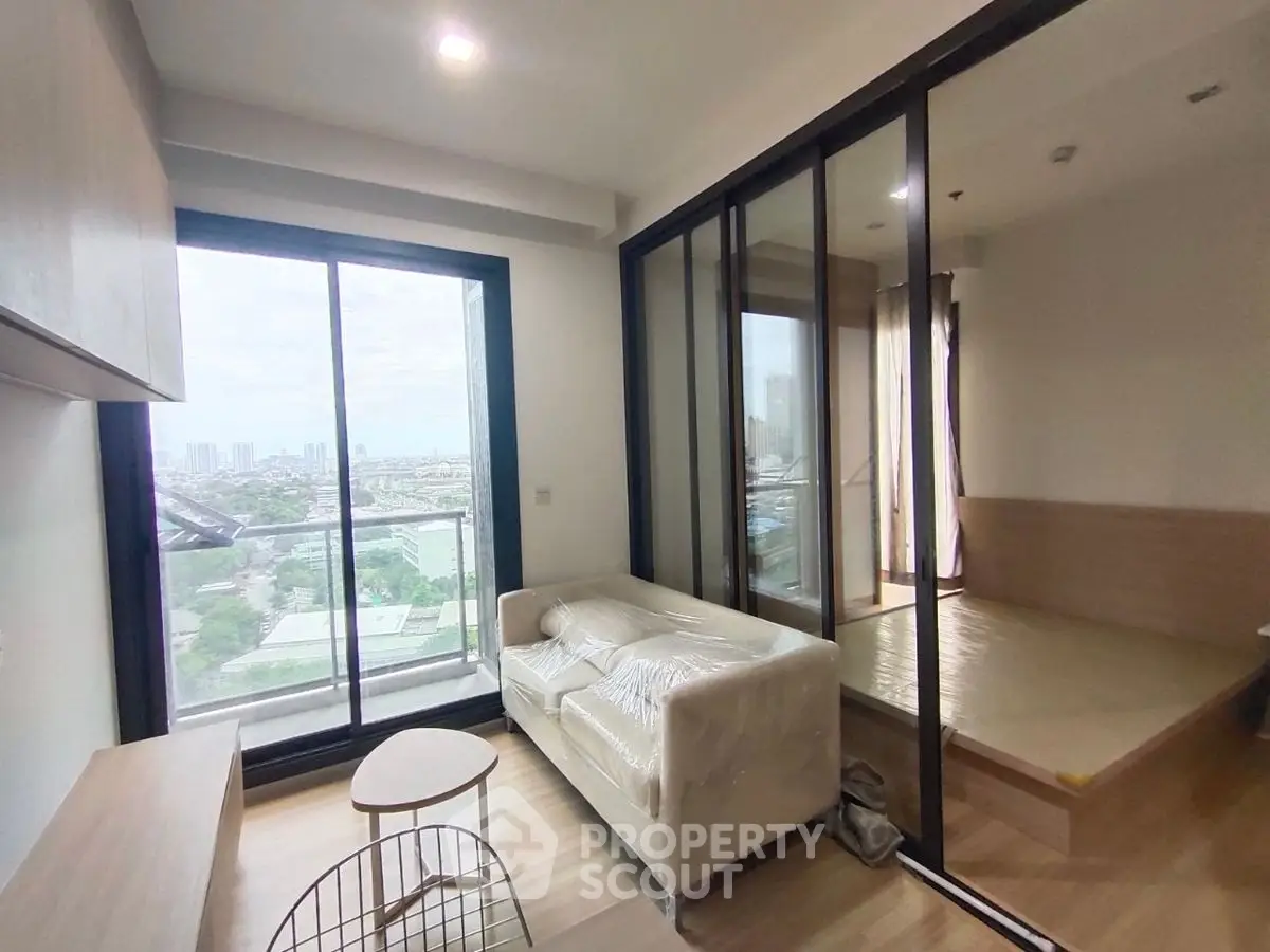 Modern condo with city view, featuring cozy living room and bedroom separated by glass partition.