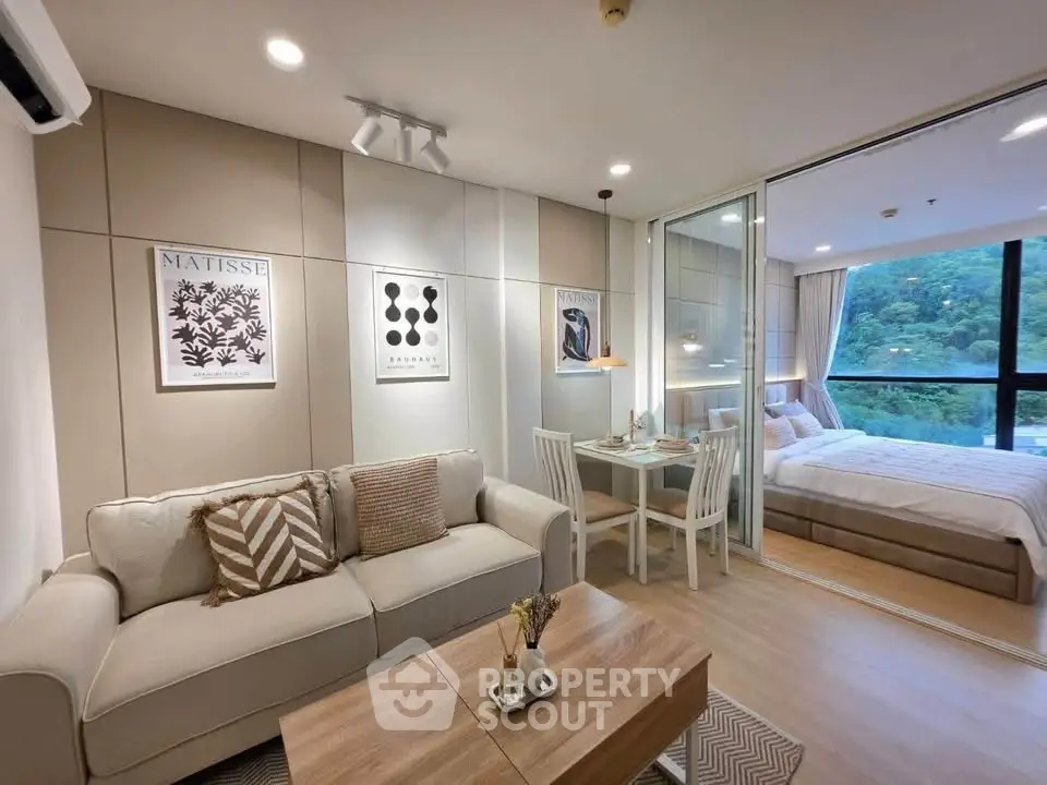 Modern open-plan living room with cozy seating and dining area, adjacent to a stylish bedroom with scenic views.