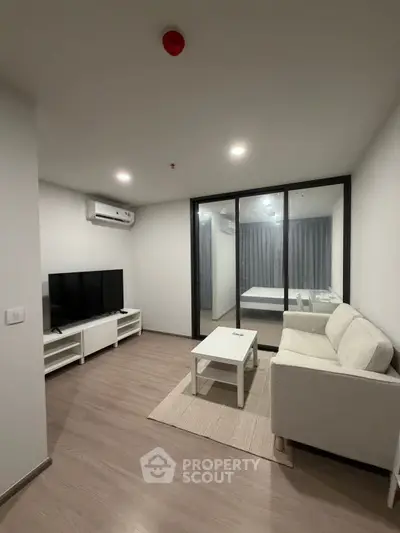 Modern living room with sleek furniture and large TV in a cozy apartment.