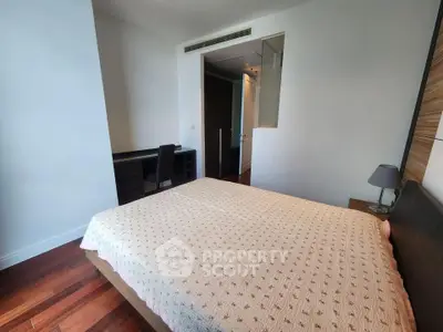 Spacious bedroom with modern decor and wooden flooring, featuring a cozy bed and a study desk.