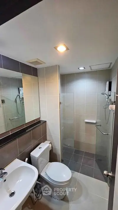 Modern bathroom with sleek fixtures and glass shower enclosure in a contemporary apartment.