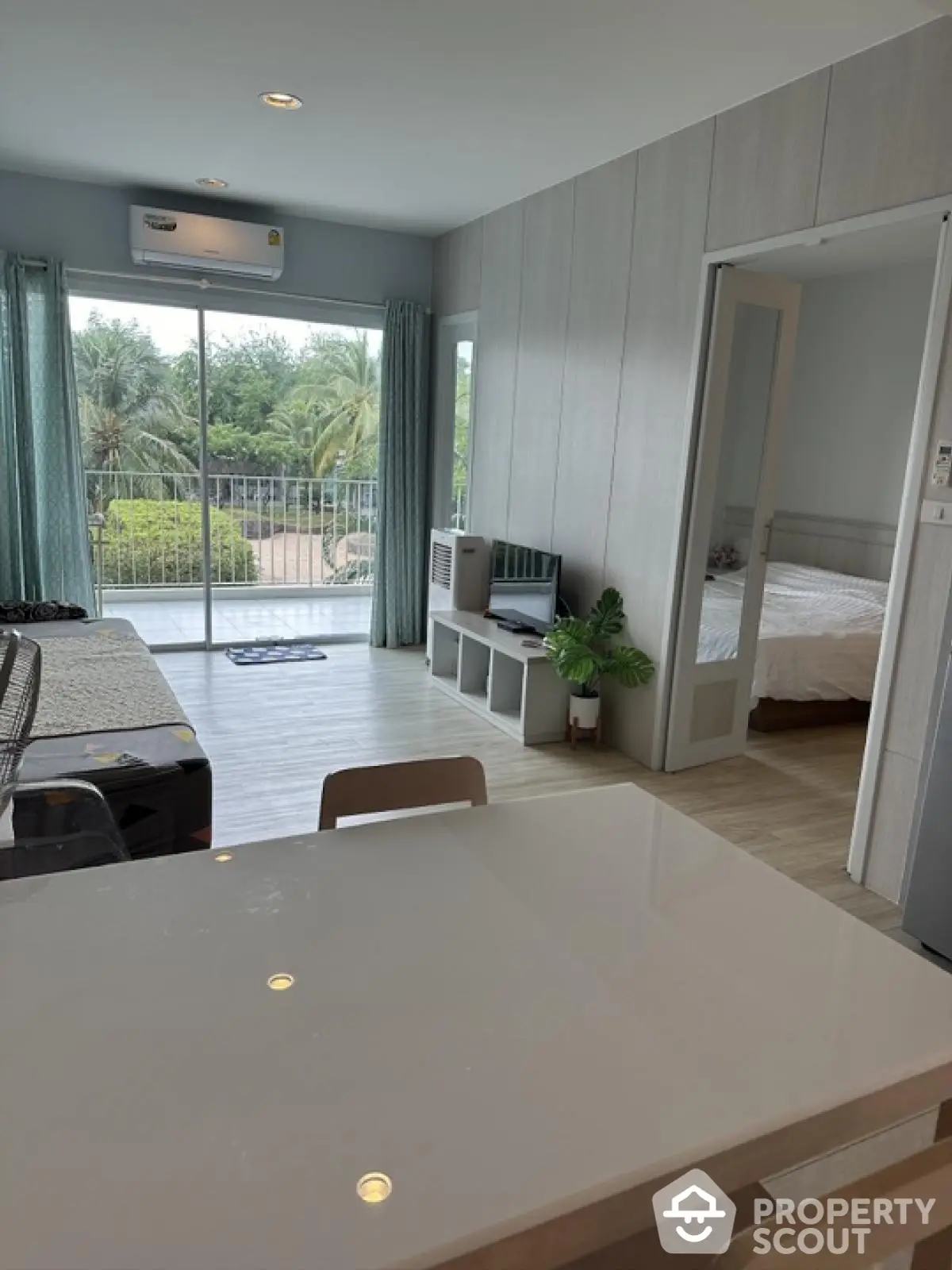 Modern open-plan living room with balcony and bedroom view