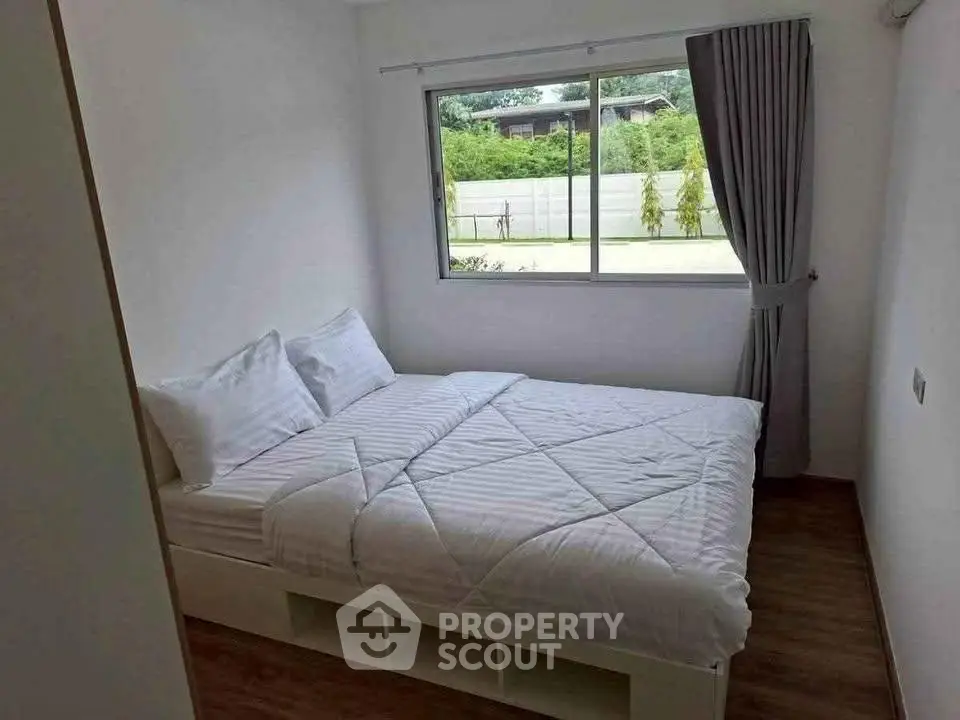 Cozy bedroom with large window and modern decor, perfect for relaxation and comfort.