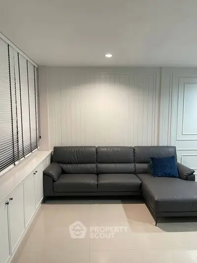Modern living room with sleek gray sectional sofa and elegant paneling, perfect for stylish relaxation.