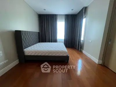 Spacious bedroom with elegant hardwood floors and large windows for natural light.