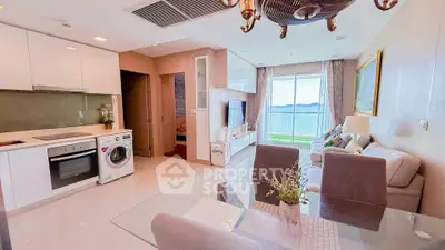 Modern open-plan living room with kitchen, featuring sea view balcony and stylish decor.