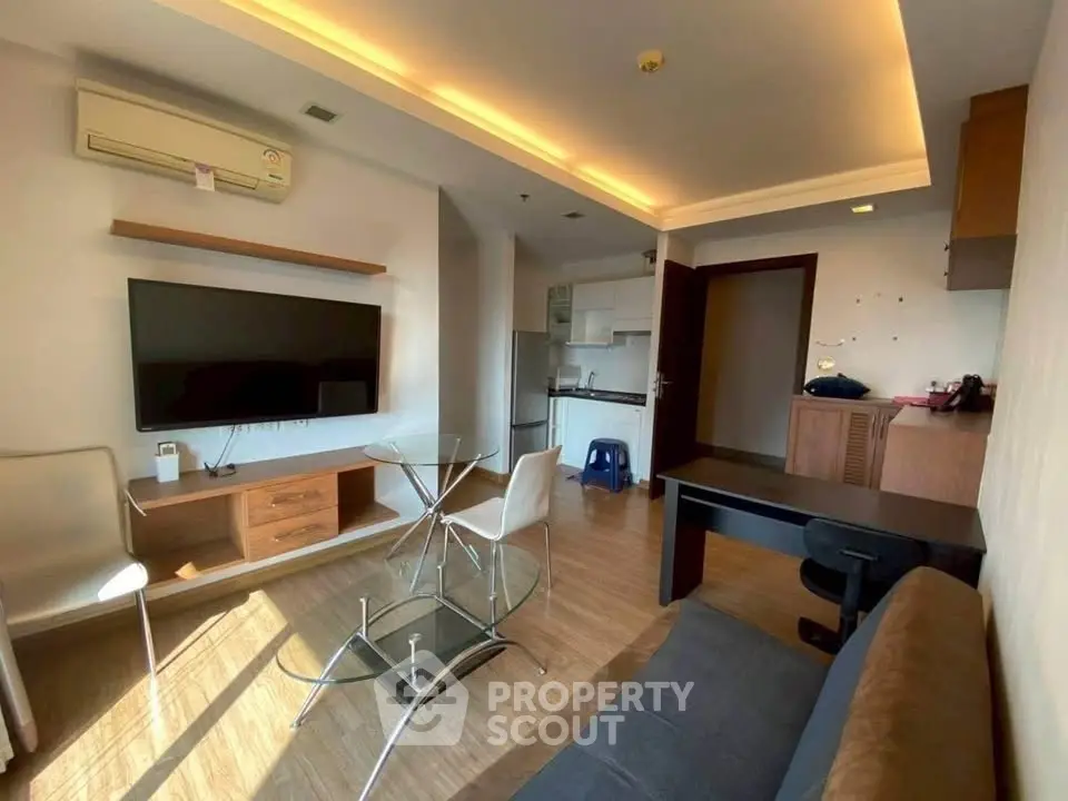 Modern living room with open kitchen, featuring sleek furniture and ambient lighting.