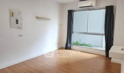 Spacious empty room with wooden flooring and large window