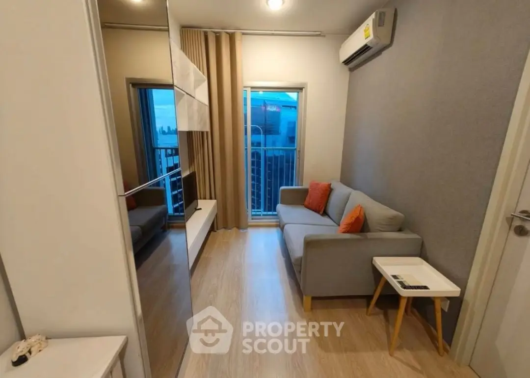 Modern living room with balcony view, stylish sofa, and sleek decor in a cozy apartment.