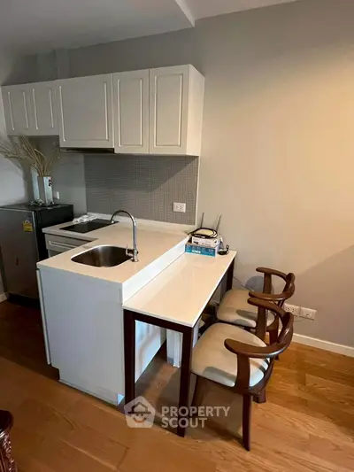 Modern compact kitchen with white cabinets and breakfast bar in cozy apartment