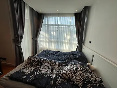 Cozy bedroom with large window and elegant curtains, perfect for relaxation.