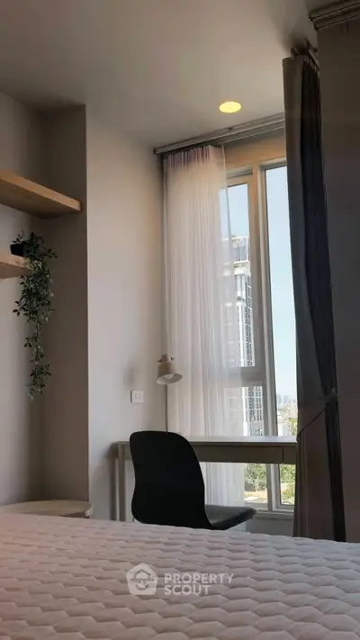 Modern bedroom with study area and city view, featuring sleek furniture and natural light.