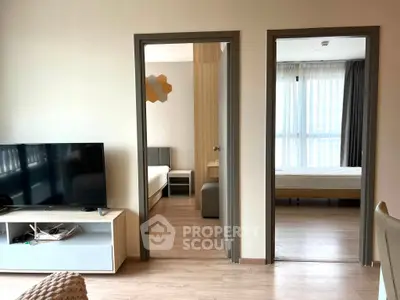 Modern apartment interior with two bedrooms and a cozy living area featuring a flat-screen TV.