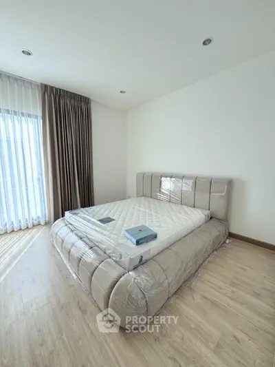 Spacious bedroom with modern bed and natural light, perfect for relaxation.