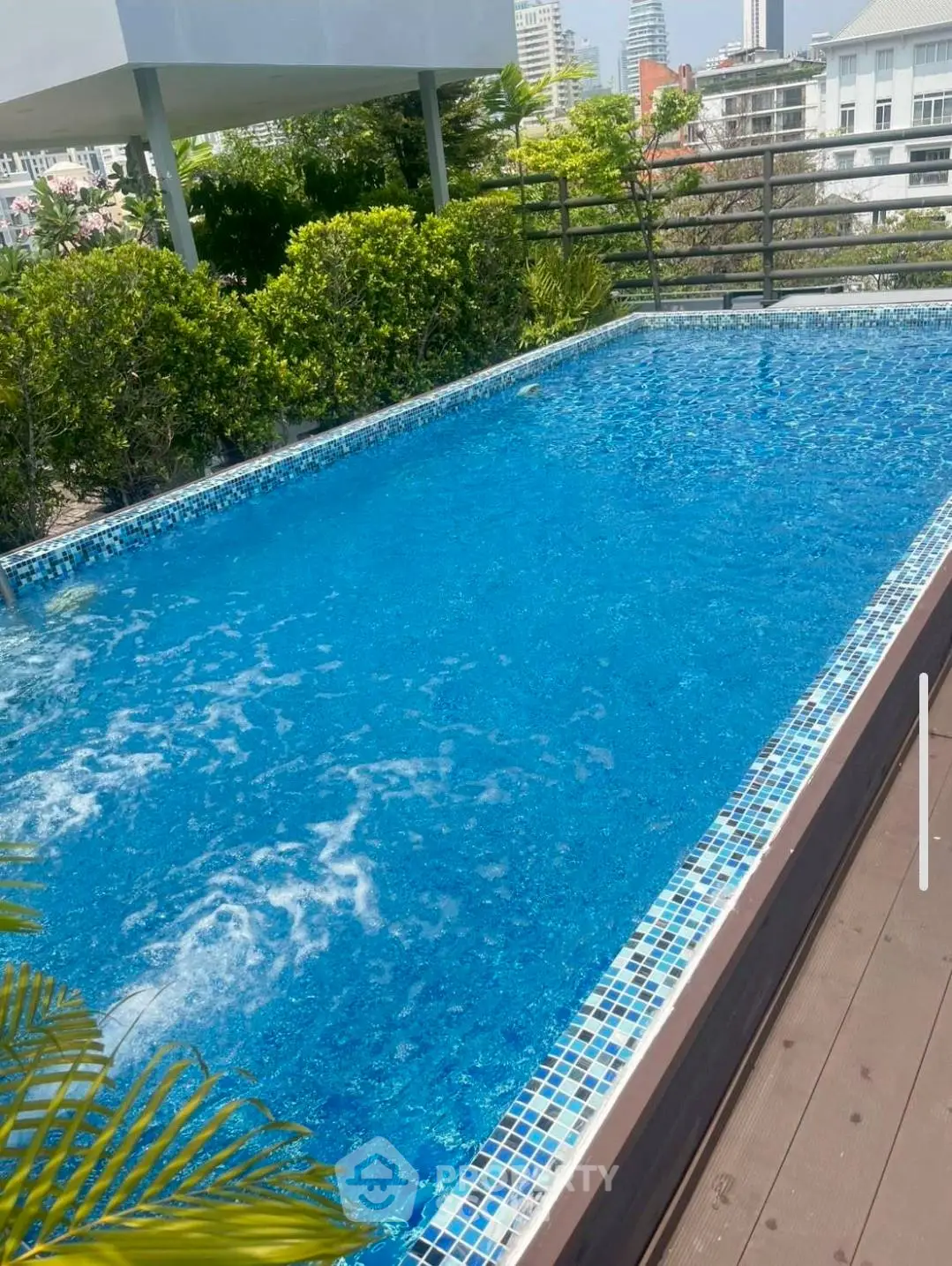 Luxurious rooftop pool with stunning city views and lush greenery, perfect for relaxation and leisure.