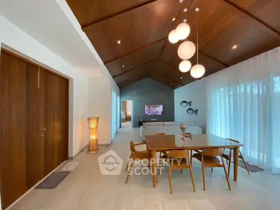 Elegant dining area with wooden ceiling and modern lighting in a spacious open-plan living room.