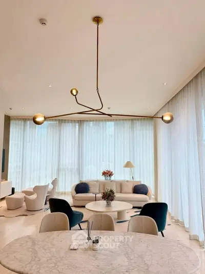 Luxurious modern living room with elegant lighting and stylish furniture, featuring a spacious open layout and large windows.