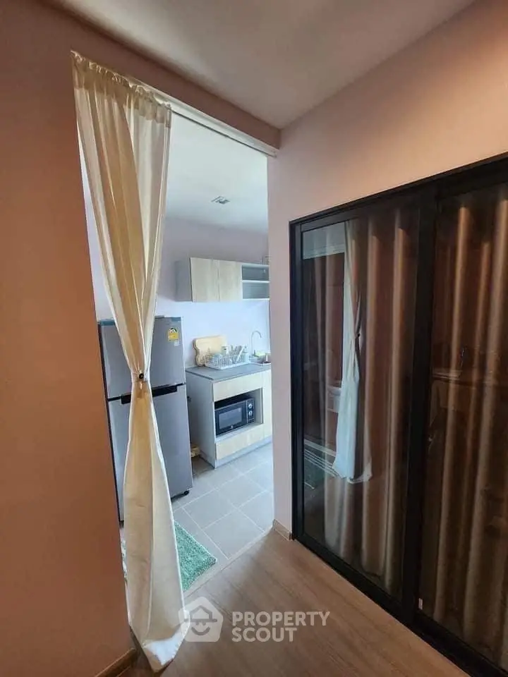 Modern kitchen with sleek appliances and sliding glass door in cozy apartment.