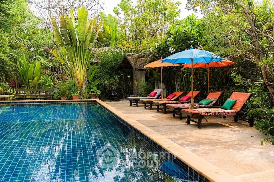 Luxurious outdoor pool area with lush greenery and colorful sun loungers, perfect for relaxation and leisure.