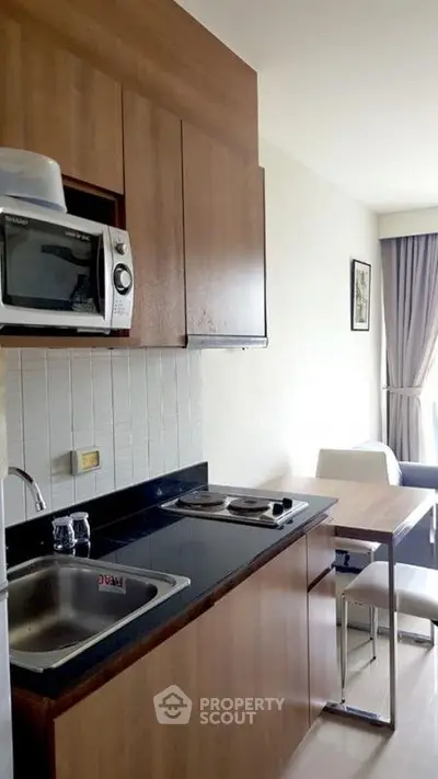 Modern compact kitchen with wooden cabinets and dining area in cozy apartment
